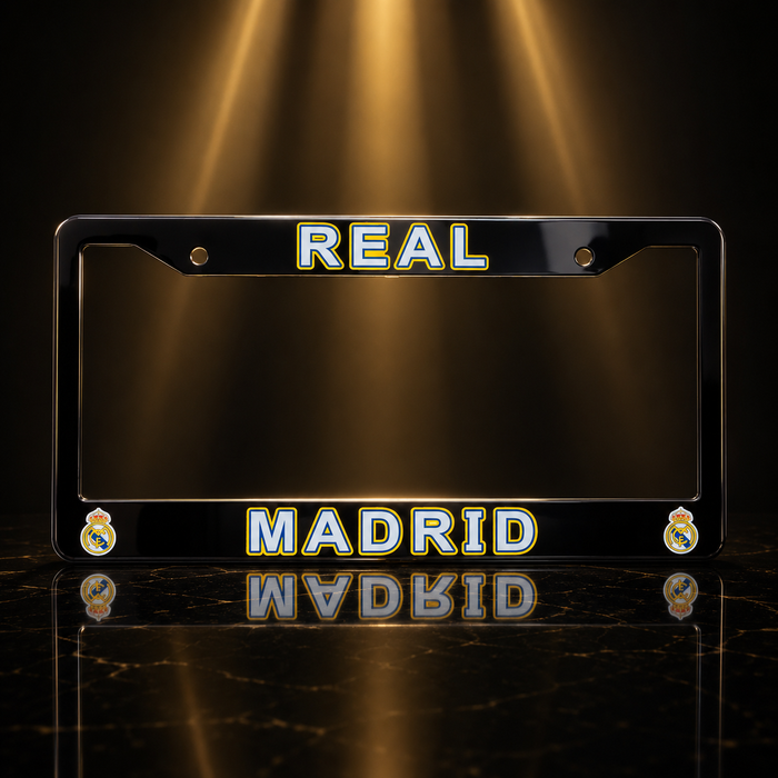 A black license plate frame featuring 'REAL MADRID' in gold and white lettering, with the Real Madrid crest in the corners, set against a dark background with dramatic golden spotlights.