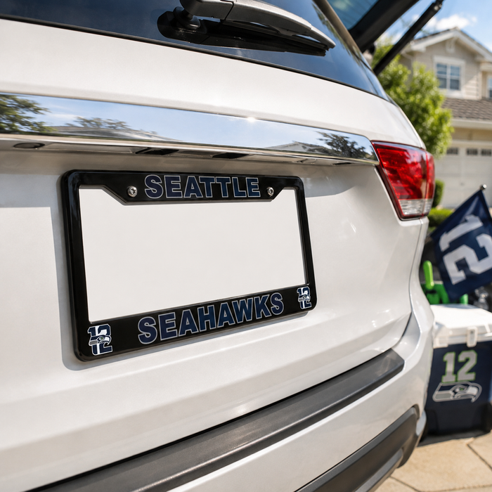 A black Seattle Seahawks license plate frame mounted on the rear bumper of a white vehicle, with the Seahawks logo and team name in blue and white.