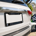A black Seattle Seahawks license plate frame mounted on the rear bumper of a white vehicle, with the Seahawks logo and team name in blue and white.